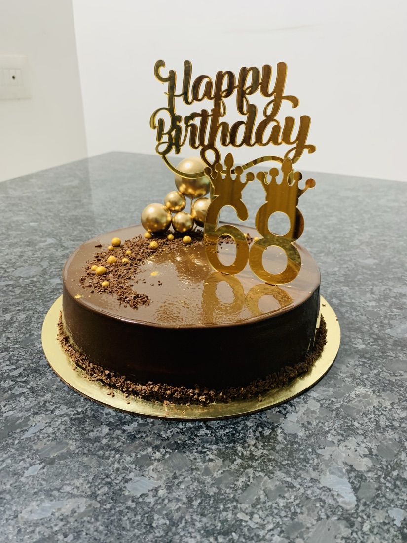 Glossy dark chocolate mirror-glaze birthday cake with gold accents